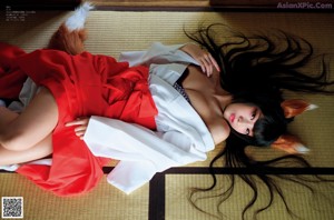 A woman in a white kimono laying on a bed.