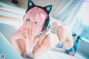 A woman with pink hair wearing a cat ears headband.