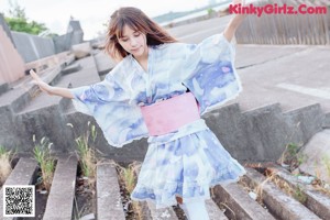 A woman in a blue kimono holding a flower in her hand.