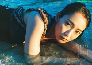 A woman sitting in the water on a beach.