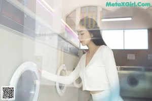 A woman is standing in front of a washing machine.