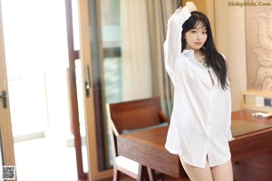 A woman in a white shirt and gray panties standing in front of a desk.