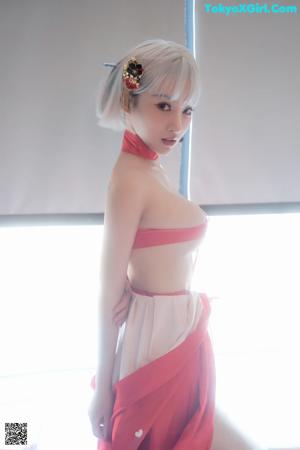 A woman in a red kimono sitting in a bathtub.