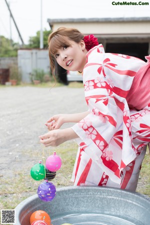 A woman in a red and white kimono posing for the camera.