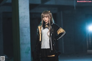 A woman in a black and yellow jacket holding a gun.