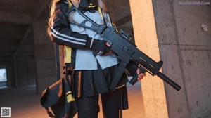 A woman in a black and yellow outfit holding a rifle.