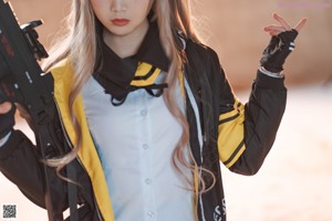 A woman in a black and yellow outfit holding a rifle.