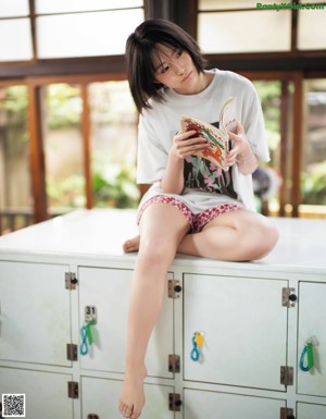 A woman in a yellow shirt is washing clothes in a laundry room.