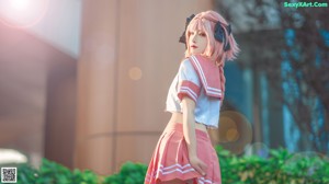A woman in a pink and white uniform leaning against a wall.