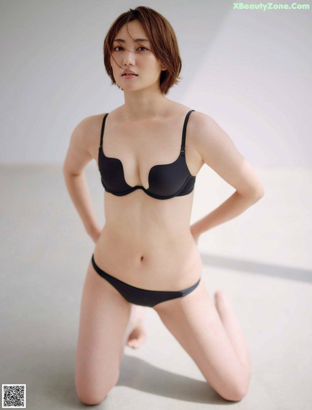 A woman in a black bra and panties posing for a picture.