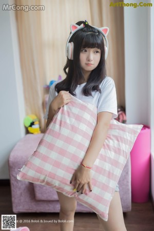 A woman sitting on a bed with headphones on.