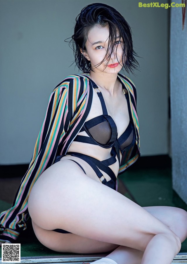 A woman in a black bikini sitting on the ground.