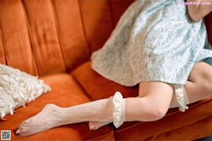 A woman is sitting on a couch with her legs crossed.
