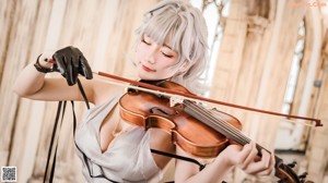 A woman in a gray dress holding a violin.