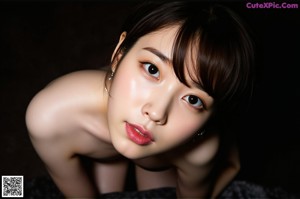 A naked asian woman standing in front of a window.