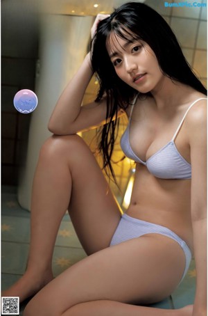 A woman in a white bikini sitting on a blue chair.