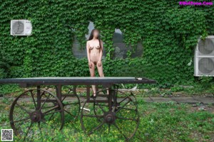 A naked woman standing on top of a wooden table.