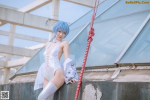 A woman with blue hair sitting on a metal structure.