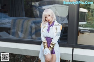 A woman in a white coat and purple skirt sitting on a wooden bridge.