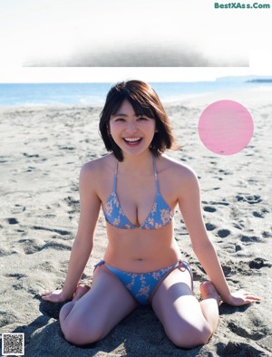 A woman in a bikini posing on the beach.