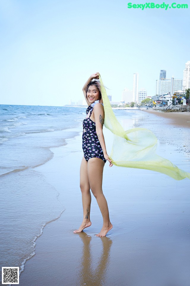 A woman in a bathing suit standing on the beach.