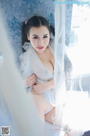 A woman in a white lingerie sitting on a bed.