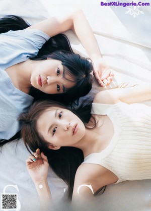 A woman sitting on top of a wooden bench next to another woman.