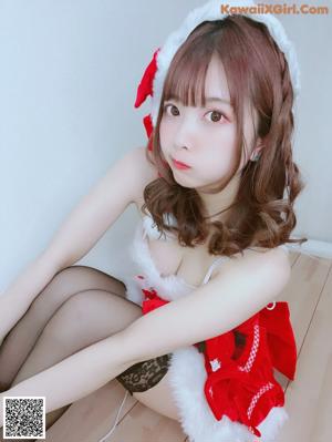 A woman in a santa hat is sitting on the floor.
