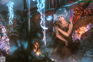 A naked woman with long blue hair sitting on a rock.