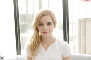 A young woman in a white top and blue jeans posing for a picture.