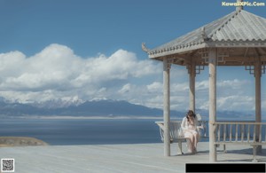 A woman sitting on top of a mountain next to a lake.