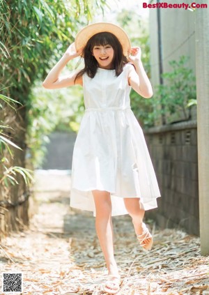 A young woman in a school uniform crouching down in the grass.