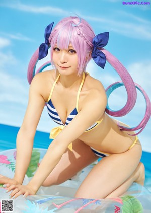 A woman in a bikini and sunglasses posing by a pool.