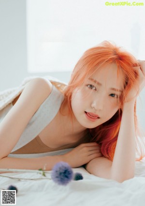 A woman laying on a bed with a flower in her hand.